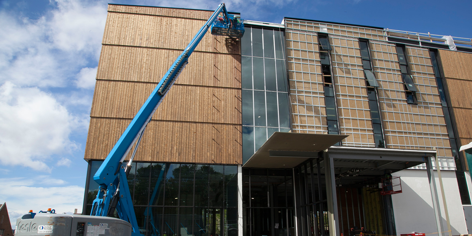 A crew member uses a lift to install siding on the New Burke exterior