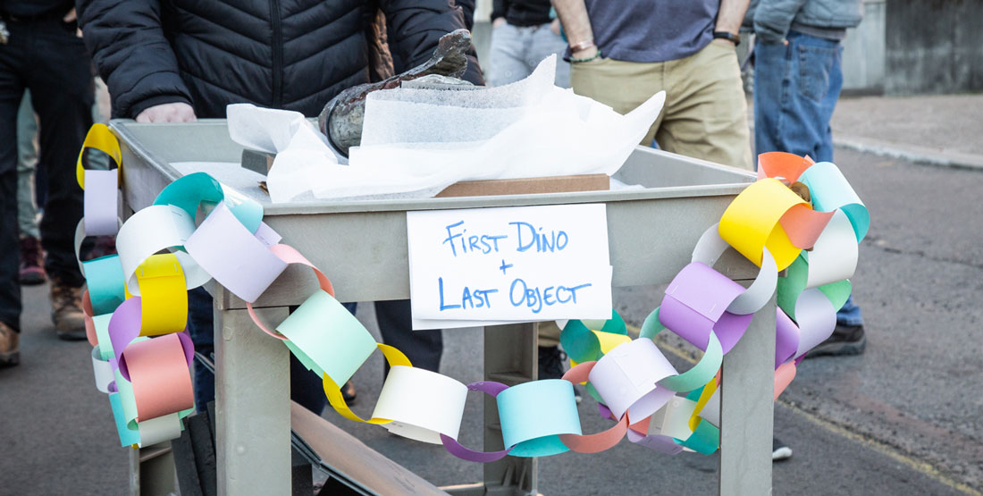 close up of the cart holding the fossil with bunting and a handmade sign that says "First Dino, Last Object"
