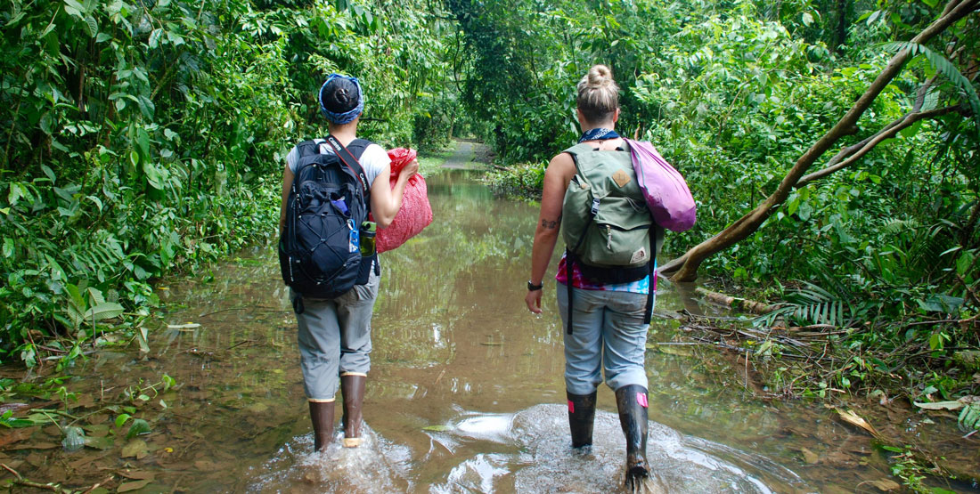 two women walk through heavy flooding while out in the field doing research