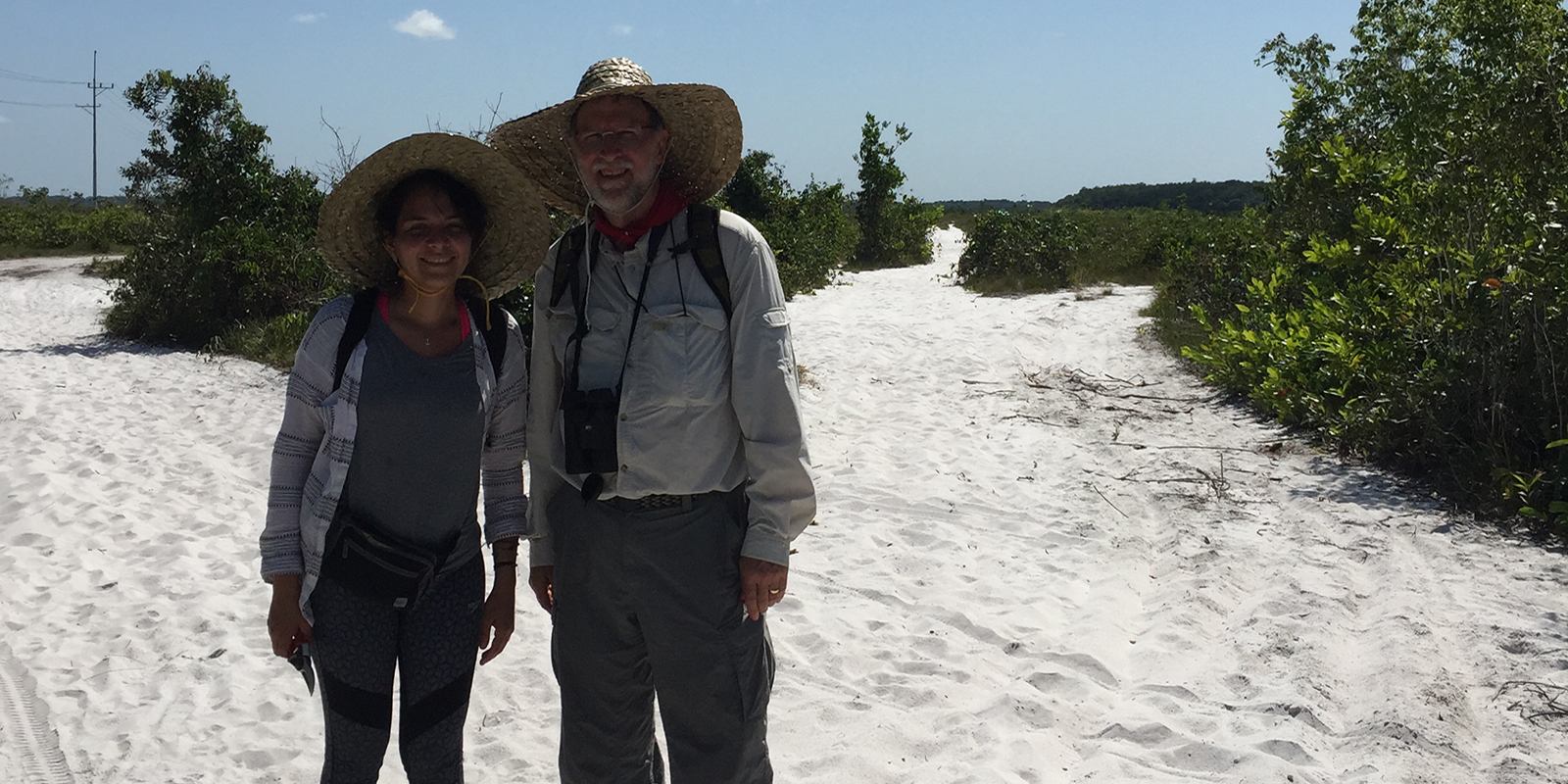 Two researchers posing outside surrounded by white sand that looks like snow