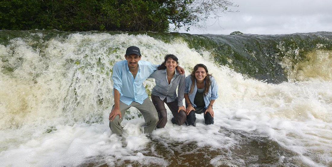 Three researchers stand in the river in the rapids