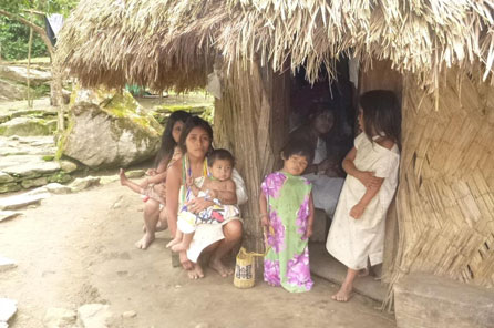 A family in front of a simple house with a thatched roof