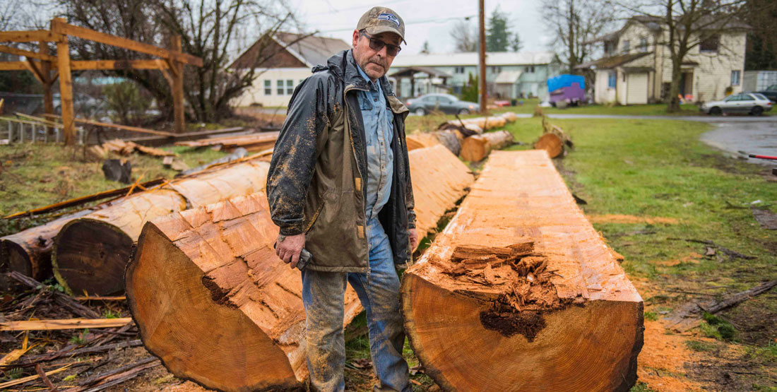 a man stands next to a massive log he just split in half