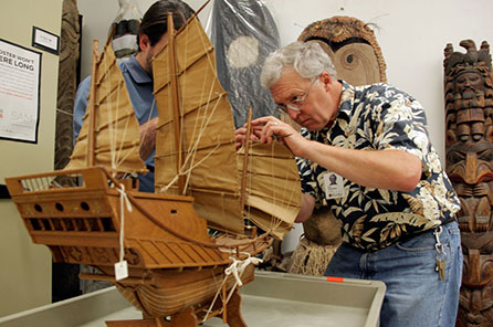 A man makes adjustments to a model boat