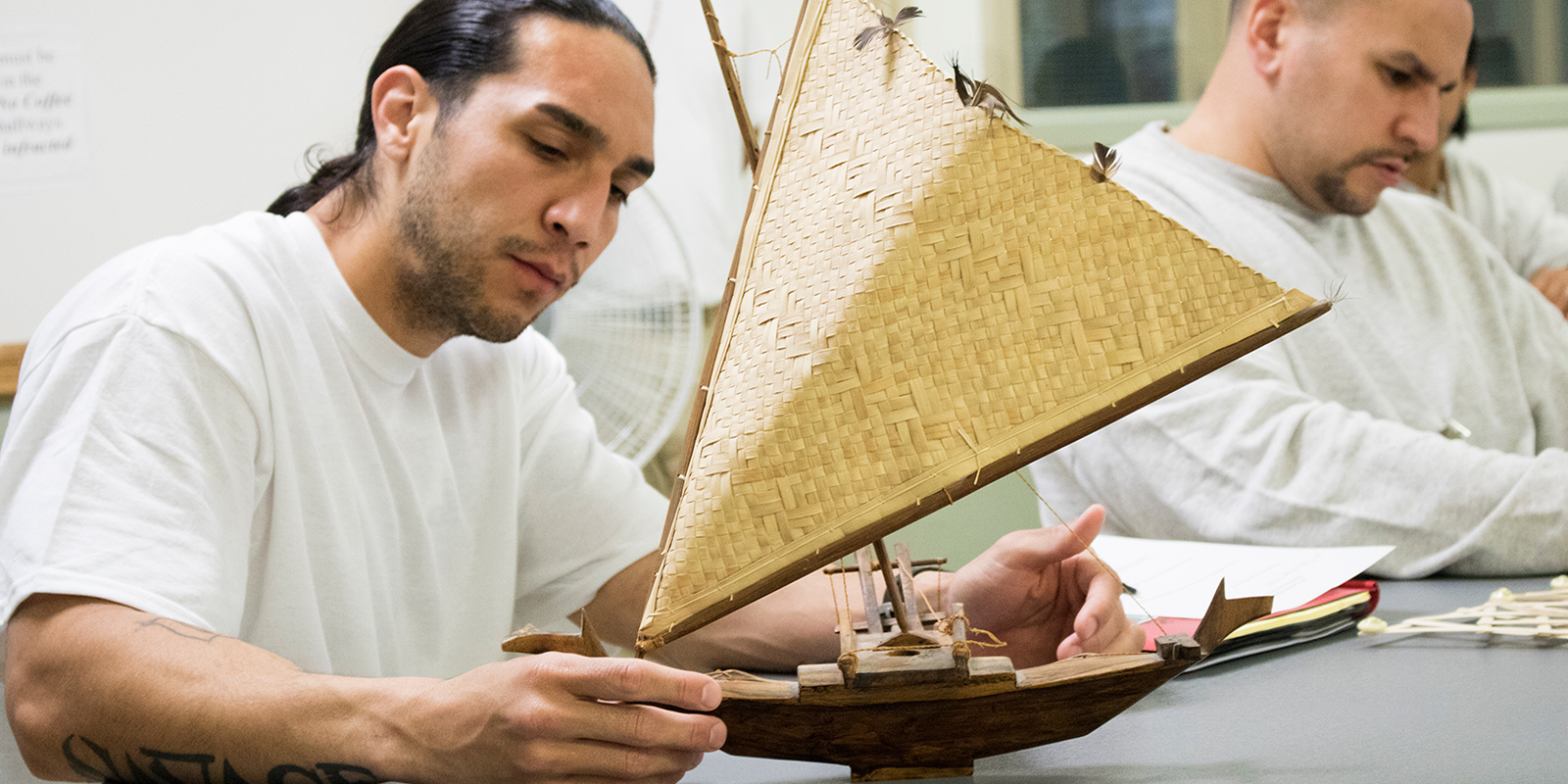 a man examines the details on a model outrigger canoe