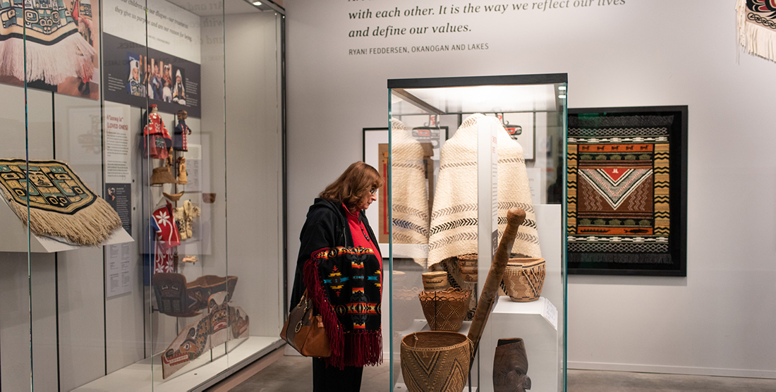 a woman looks into a case with Native American objects in it