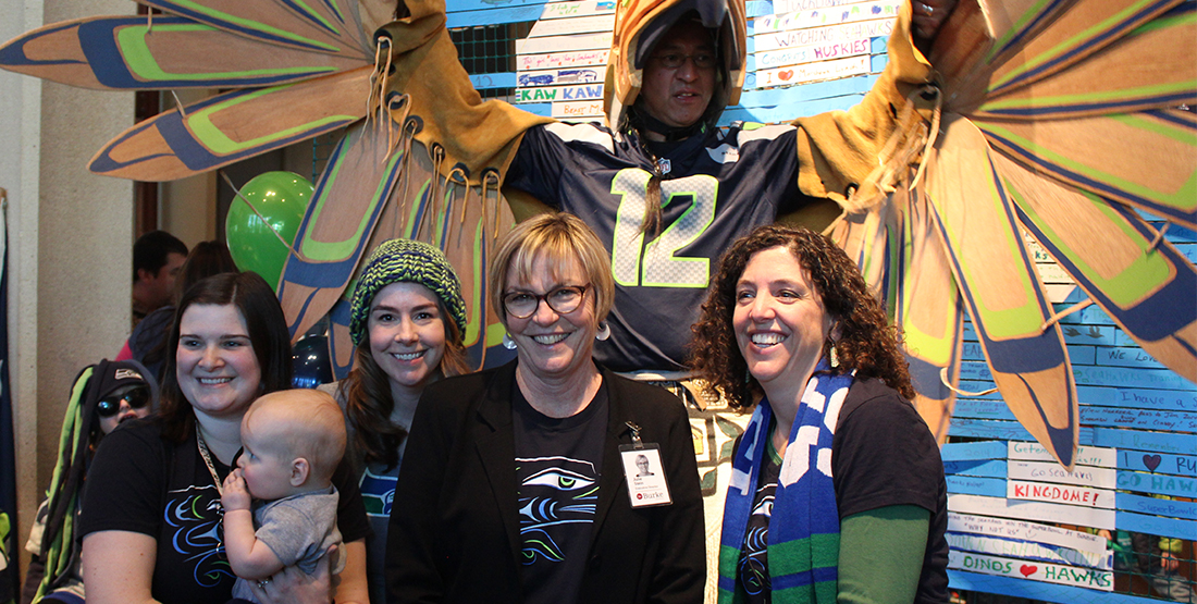 A group of women with a man dressed in wooden Seahawks regalia