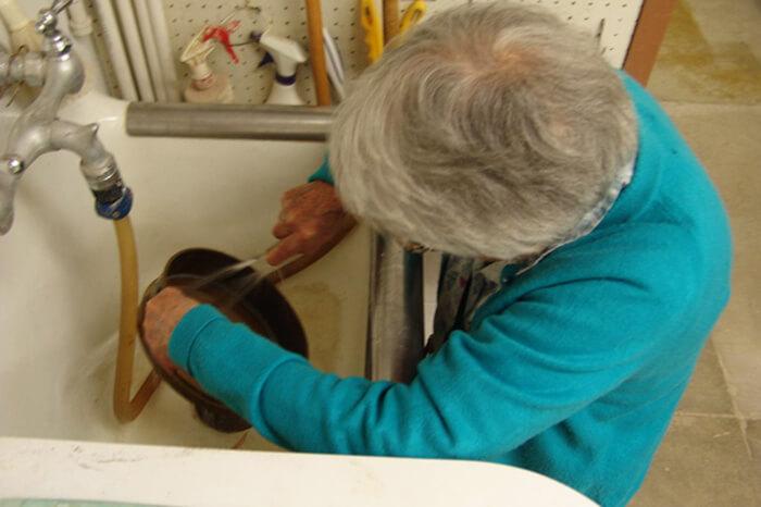 a woman rinses sediment in a sink