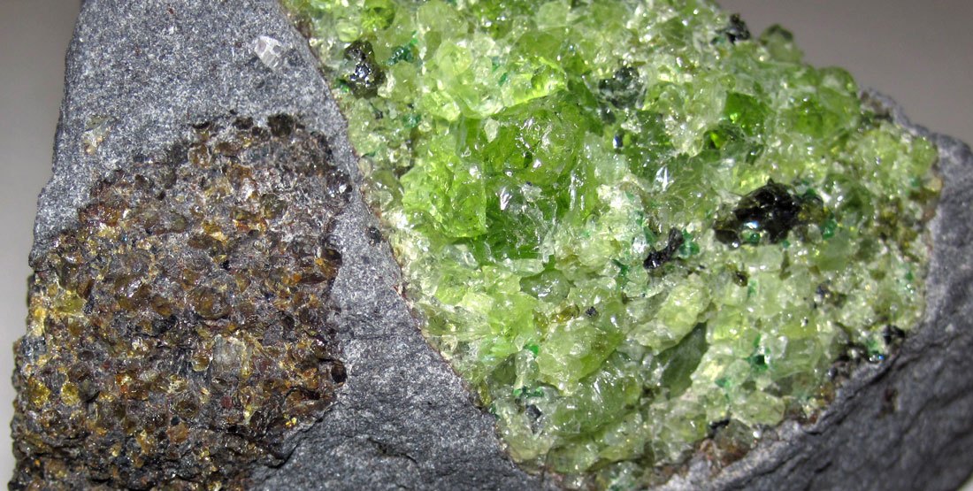 A chunk of green peridot inside a larger chunk of rock