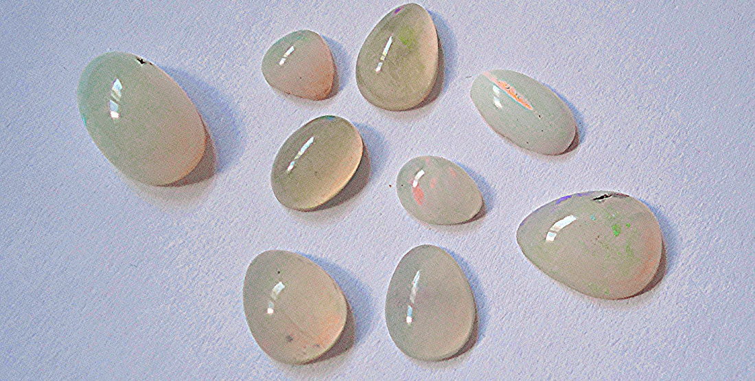 A group of small smooth round opals sit on a table