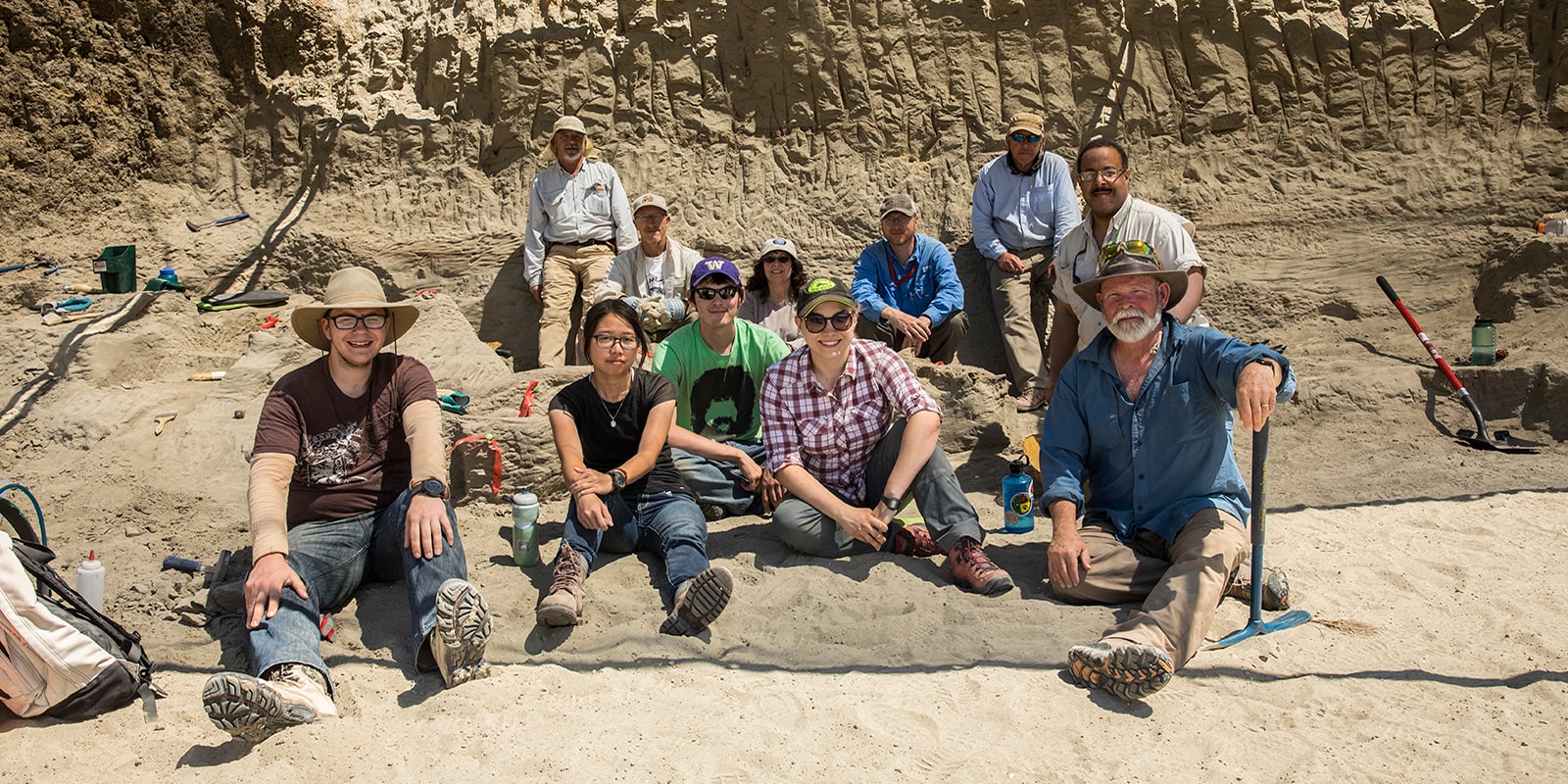 A group of eleven people posing for a group photo at a t.rex dig site
