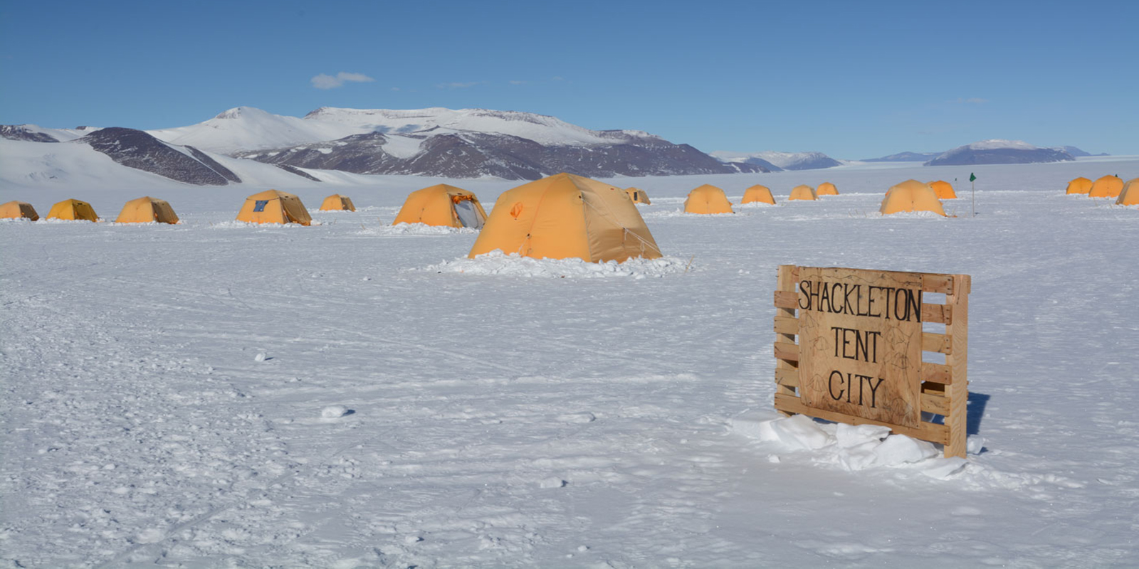yellow tents sporadically placed on the snow form a camp