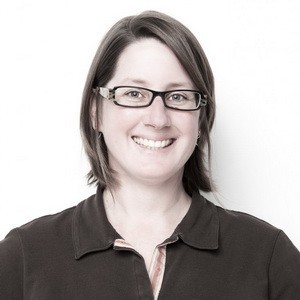 A woman with shoulder length brown hair and black square framed glasses