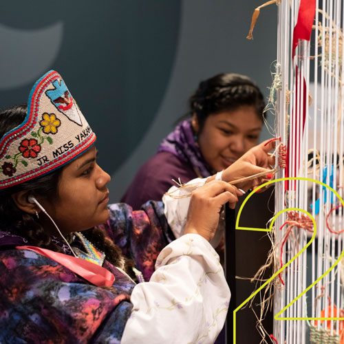 two girls tie ribbons on an interactive exhibit in the new museum