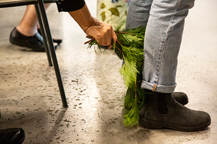 Cedar branches are brushed down to the feet of a staff member