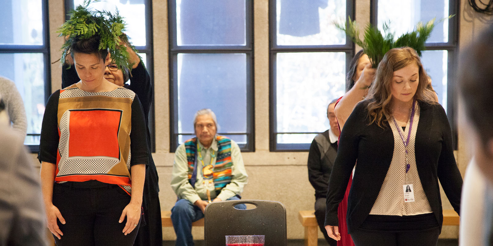 Two staff members receive the cedar brushing