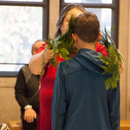 A young boy receives the cedar brushing