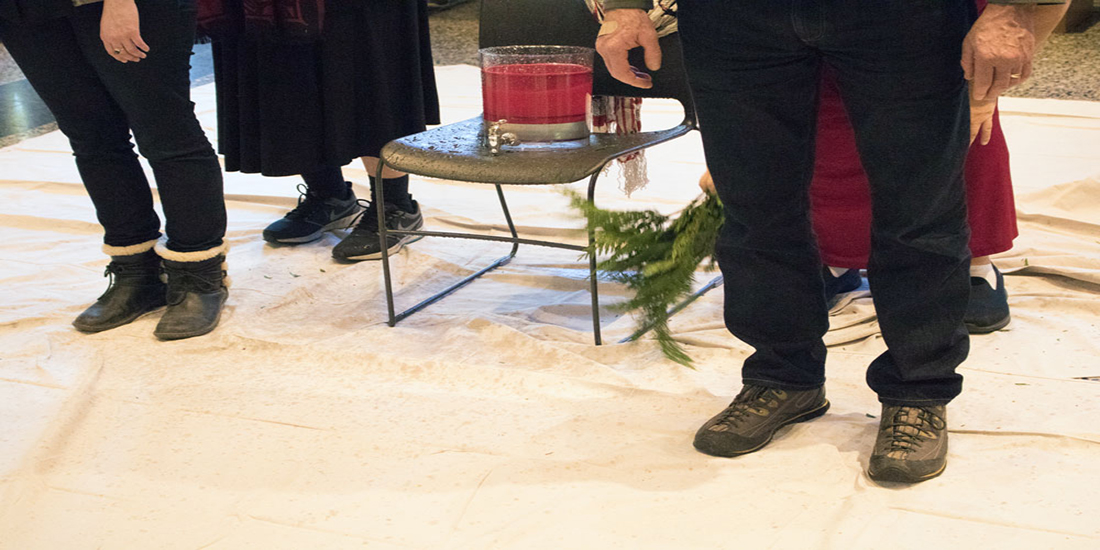 Cedar branches are brushed down to the feet of a staff member