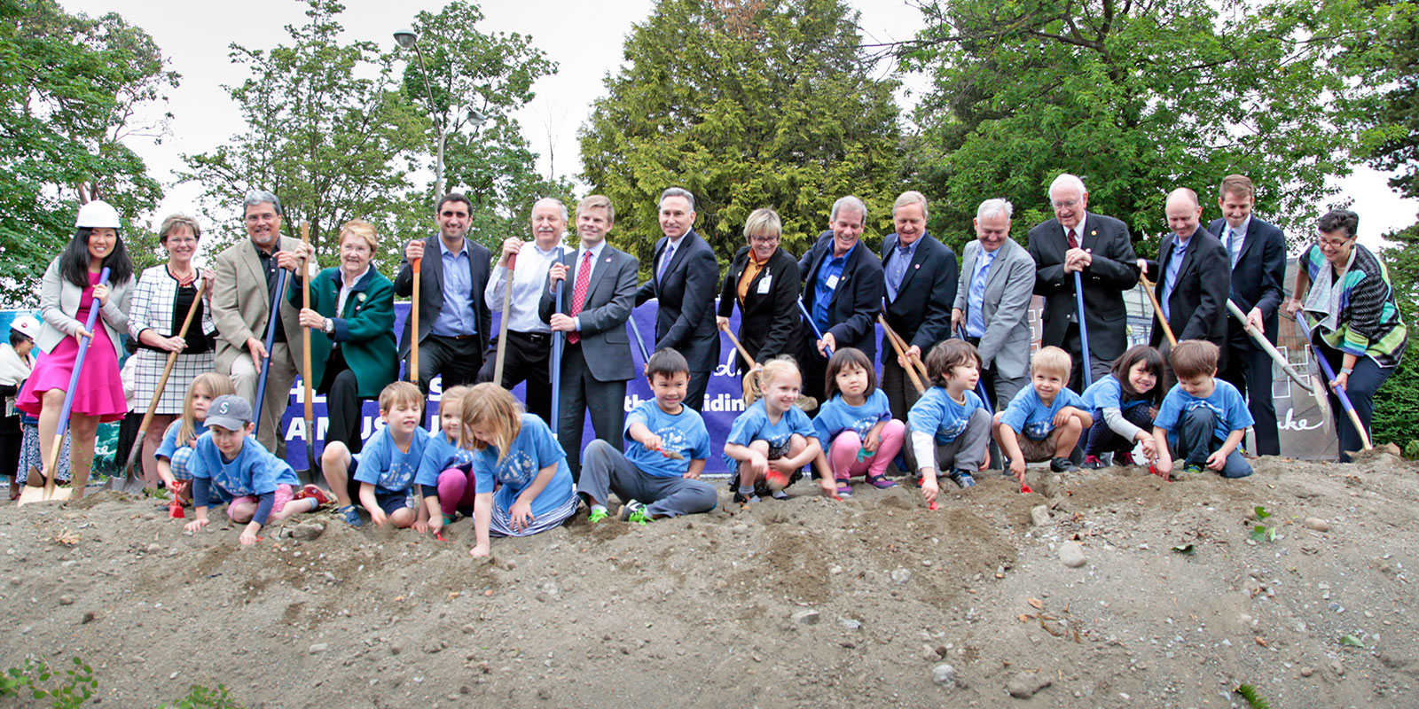 Large multi-age group standing with shovels and hard hats 