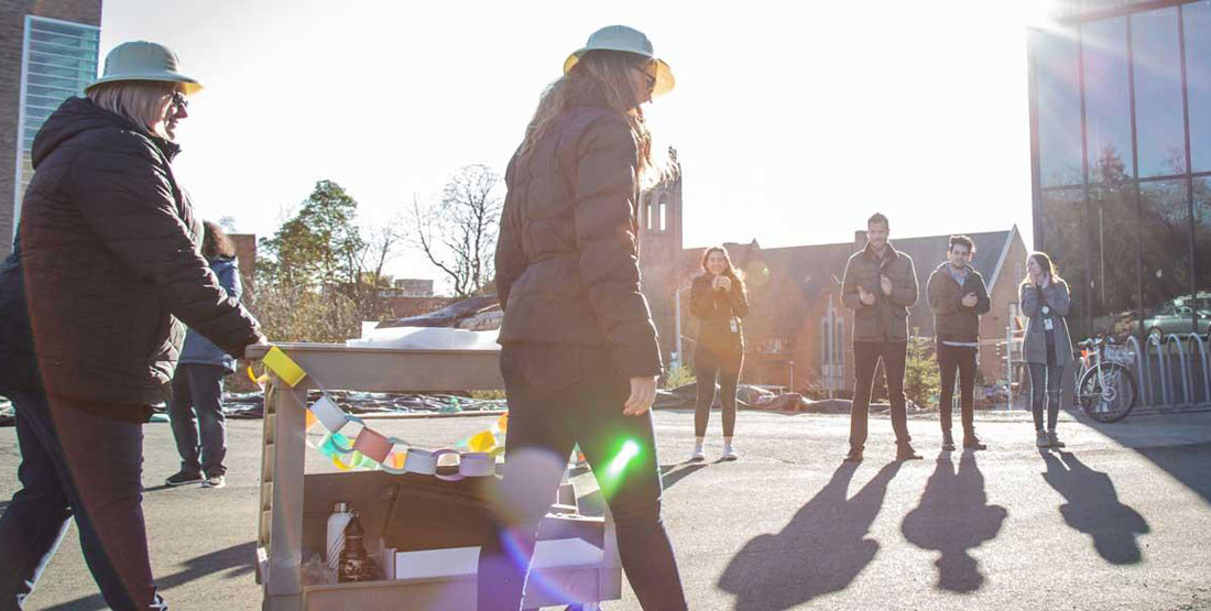 a team rolls the last object--a dinosaur fossil--on a cart as other staff cheer them on