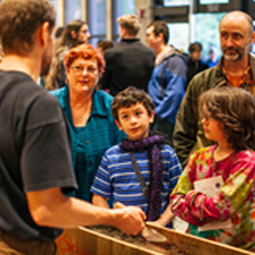 a family stands and talks to a museum collections staff member at an event