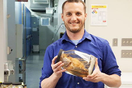 A male researcher holds a jar with a fish inside