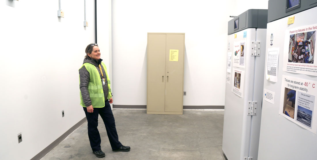 a woman smiles while standing and admiring the two freezers in their new home