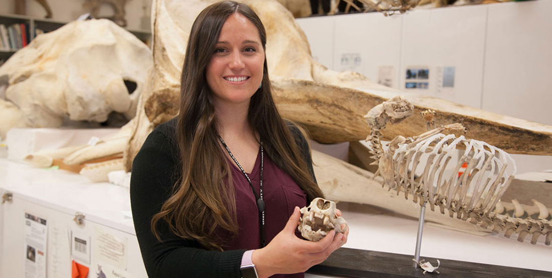 A woman researcher poses with a sea otter skull