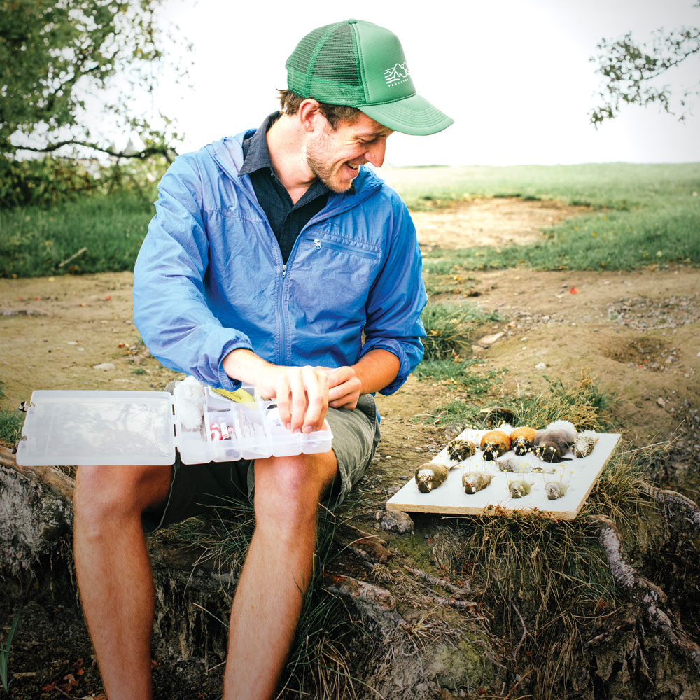 A male researcher in a green baseball cap prepares his tools for examining the birds he has collected