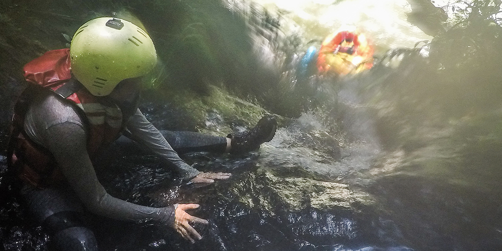 A researcher wearing a helment and life jacket rafting on a river 