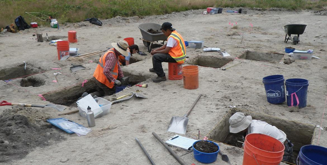 People working on a dig site with square holes in the ground 