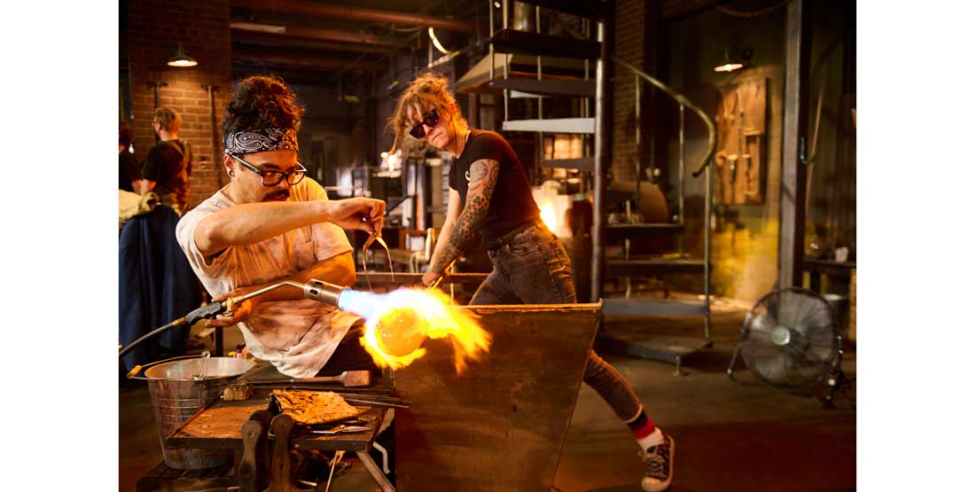 trenton quiocho works on a glass piece in a hot shop