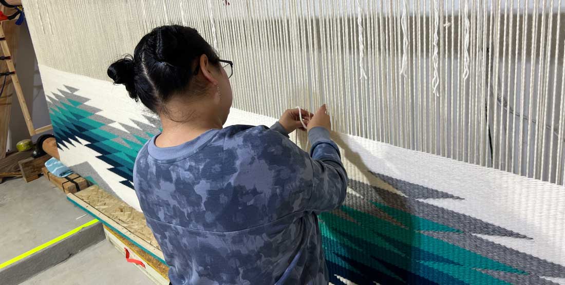 Danielle Morsette weaves on a large loom