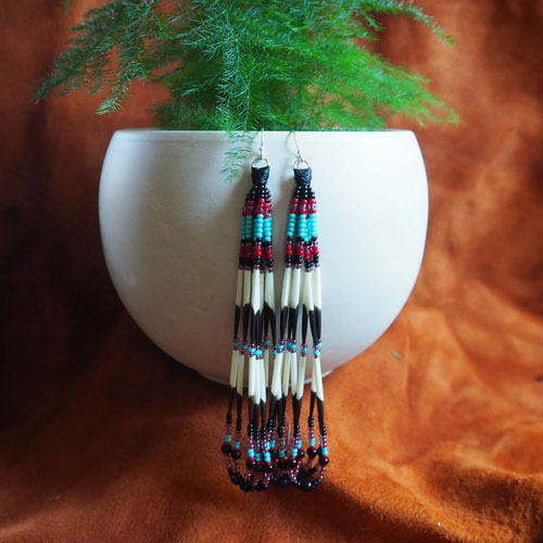 porcupine and glass bead earrings dangle from the edge of a plant pot