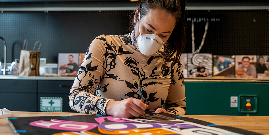 a woman paints a colorful mural at a table