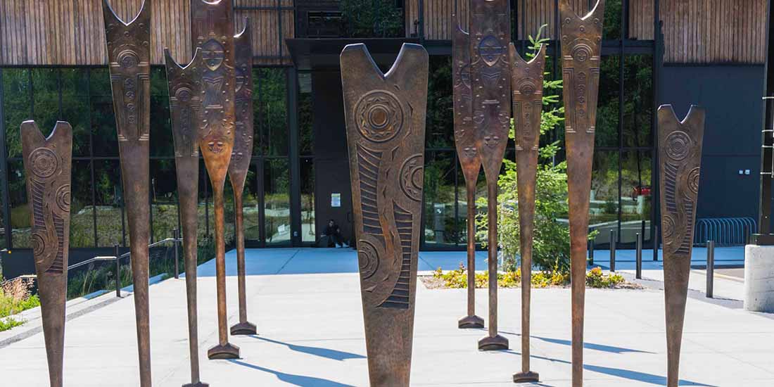 Details of figures carved into bronze paddles