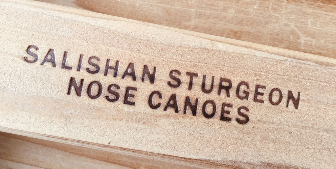 Wood with "Salishan Sturgeon Nose Canoes" branded on it