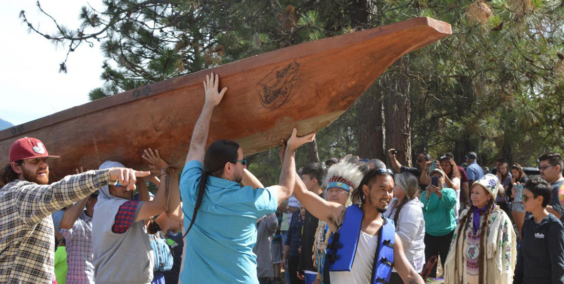 A group of people hold a canoe over their heads