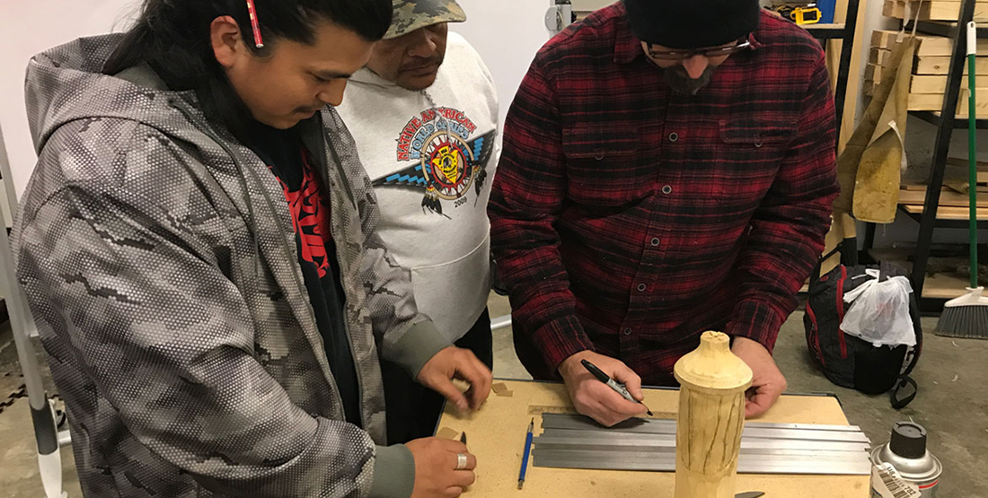 Three men measure and mark material used to make knives