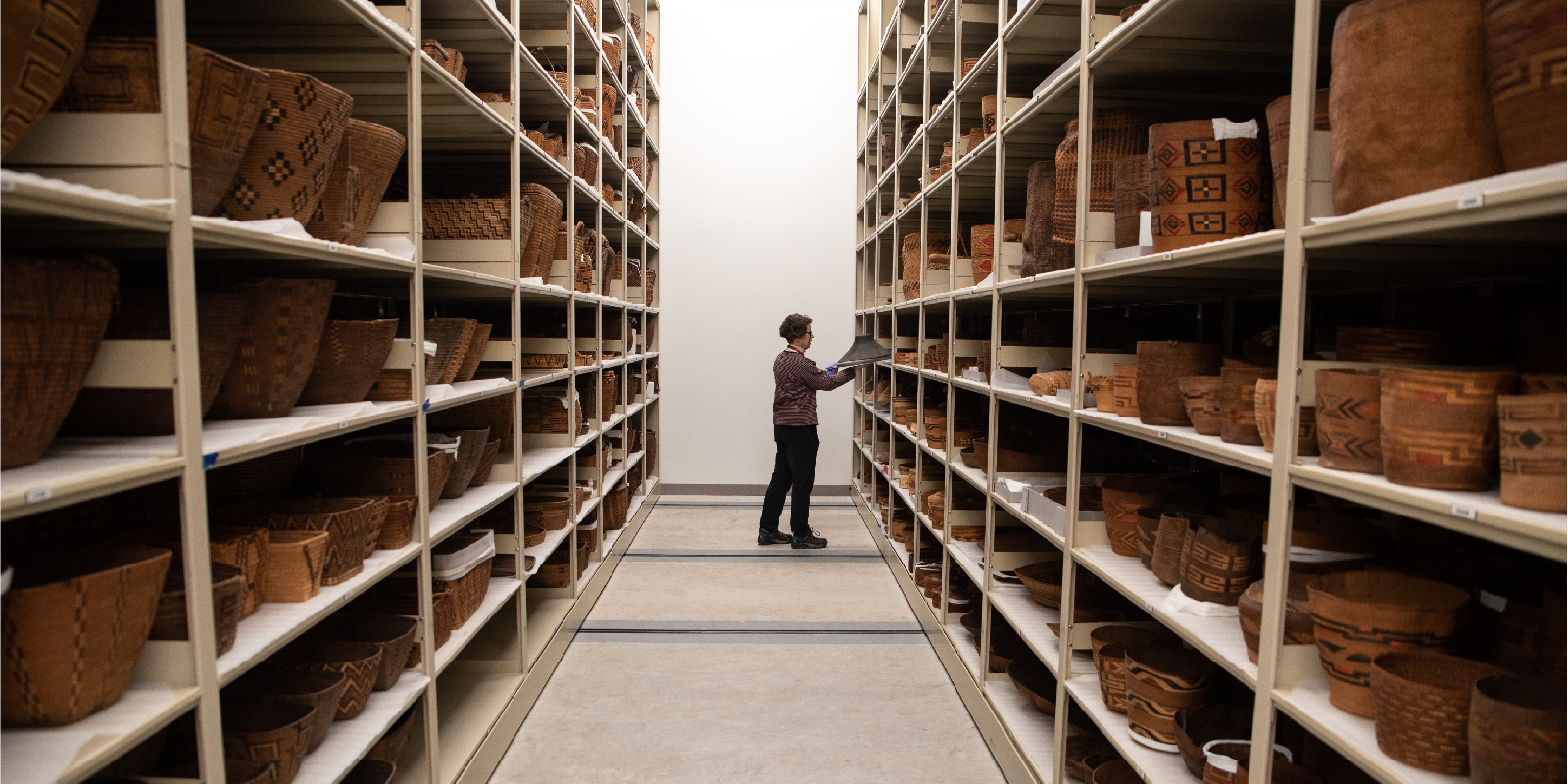 Rebecca Andrews, the Collections Manager of North and South American Cultures, examines a basket in the dedicated basketry collections room in the Burke Museum.