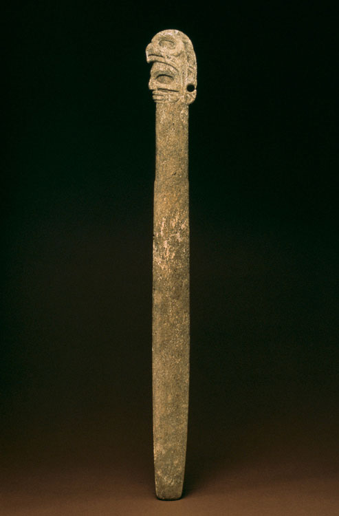 A long pointy pin decorated with a depiction of a human head wearing a headdress