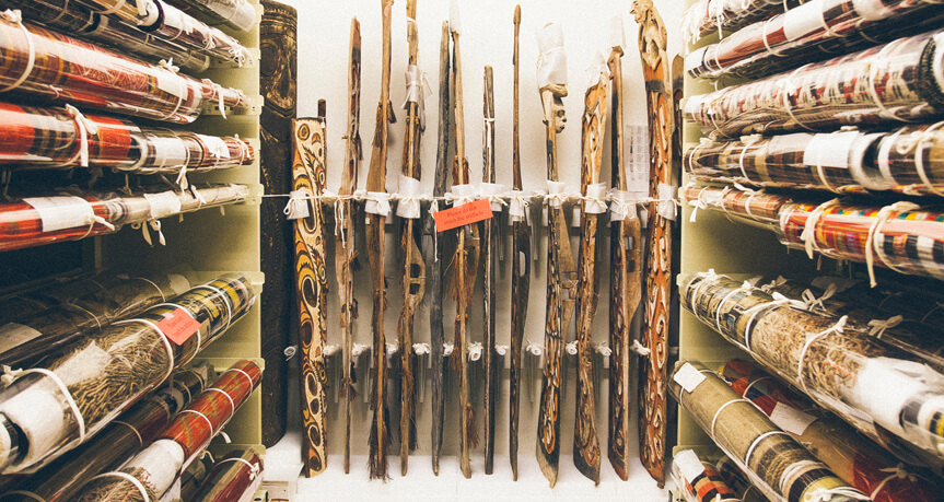 a row of textiles from Asia with spears against the back wall