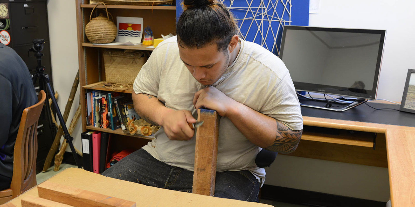 a young man carves a piece of wood