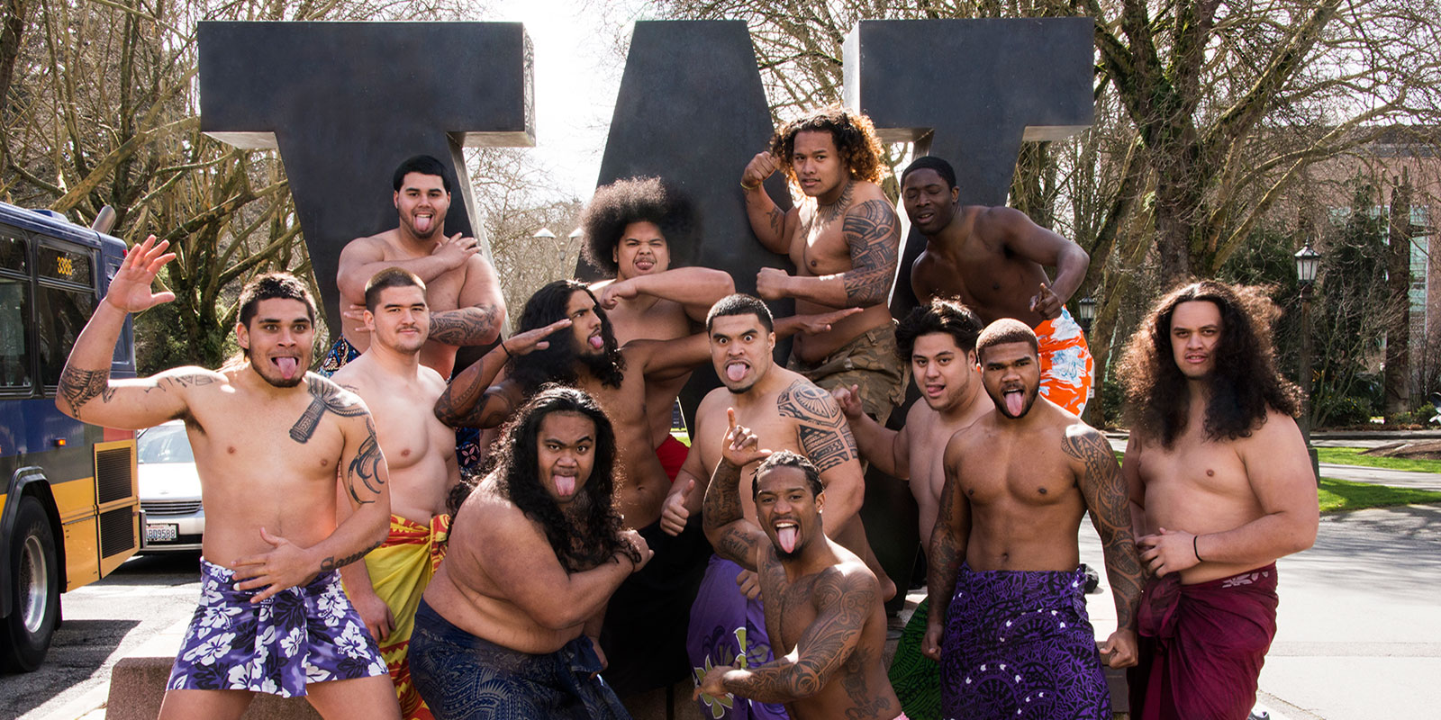 A large group of young men pose shirtless at the entrance to the UW 