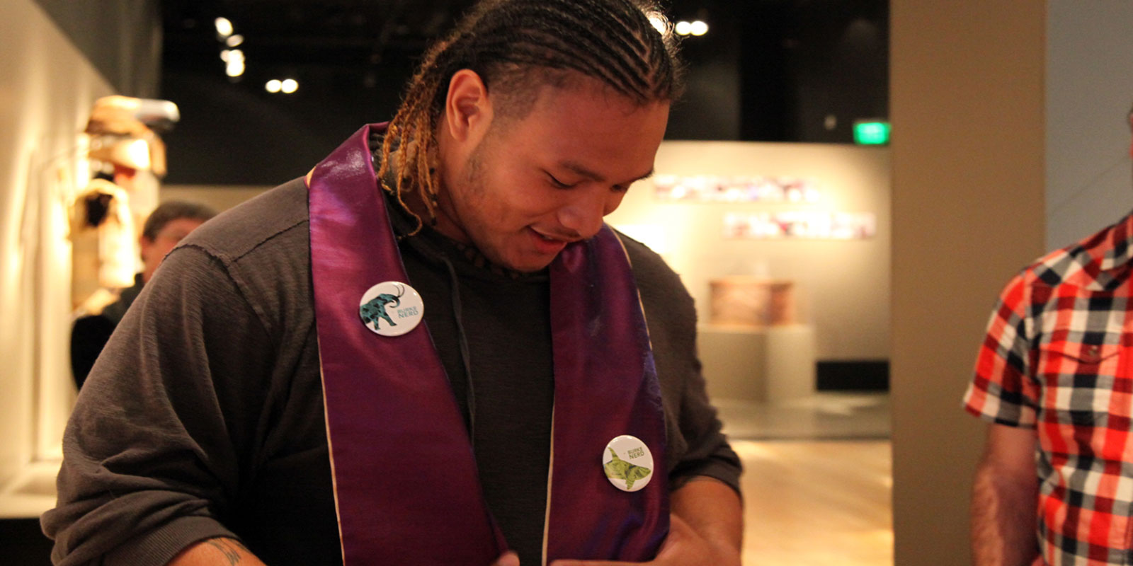 a young man looks down at a stole that was placed over his shoulders