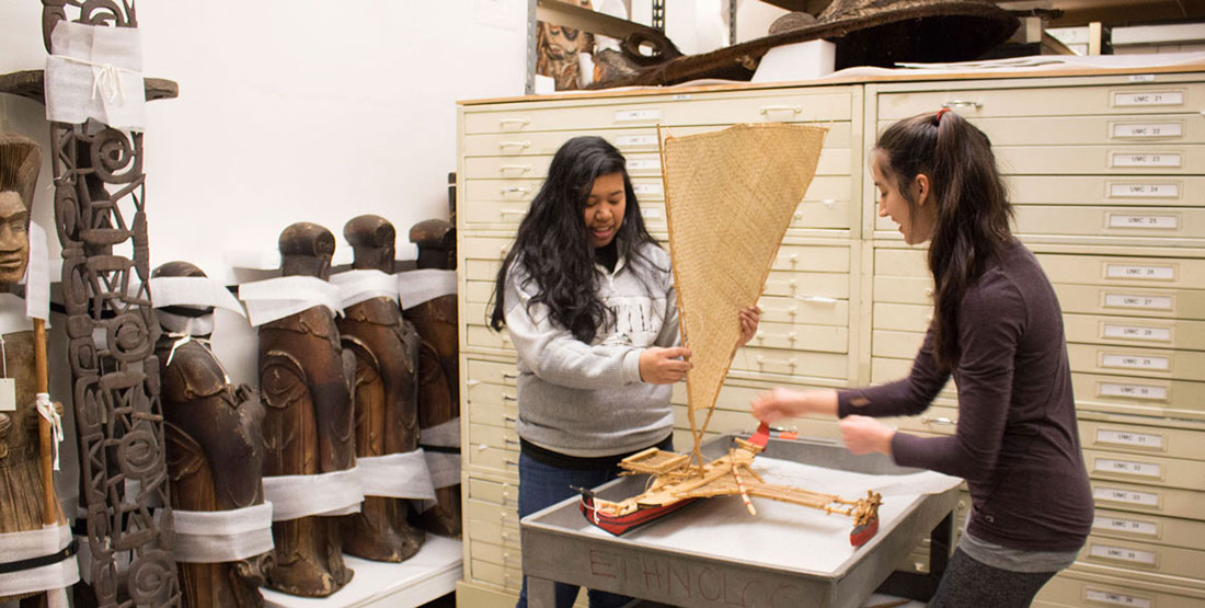 two young women adjust the sail on a model boat