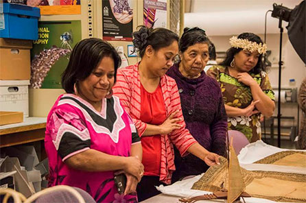 a group of women look at woven items in the Burke Museum collection