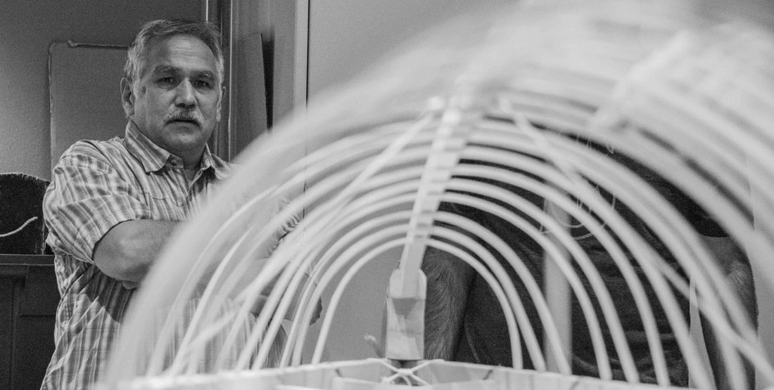 black and white photo of a man standing and looking at the kayak frame he is tying