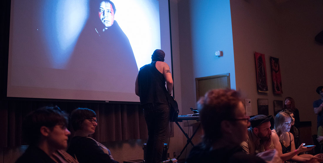 Man playing guitar with artistic video on projector screen