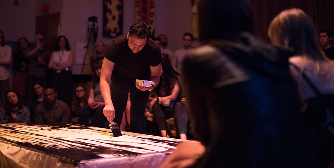 Artist holding a paintbrush painting artwork on  the ground